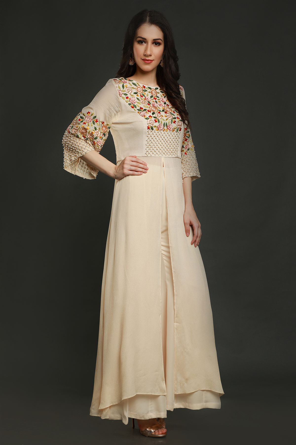 Elevate your style with a cream tunic, intricately embroidered with resham thread, pearls, and cutdana work. Paired with stylish sharara pants.