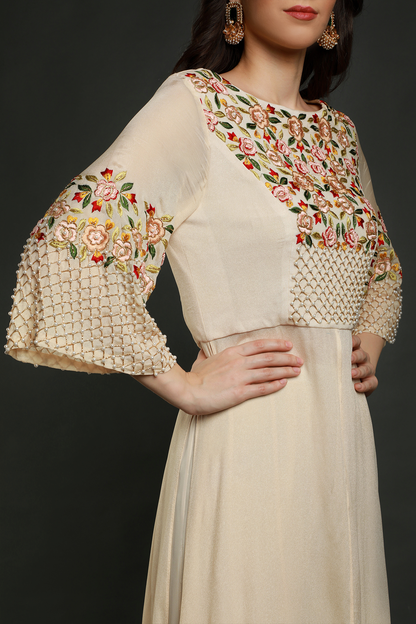 Elevate your style with a cream tunic, intricately embroidered with resham thread, pearls, and cutdana work. Paired with stylish sharara pants.