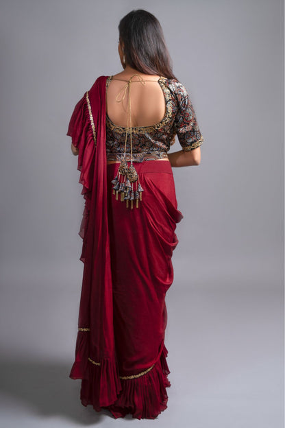 "Graceful Maroon Ruffled Saree paired with an Ajrakh Printed Blouse, featuring Intricate Embroidery in Mashru Silk. Fully Handcrafted Ajrakh Waistbelt."