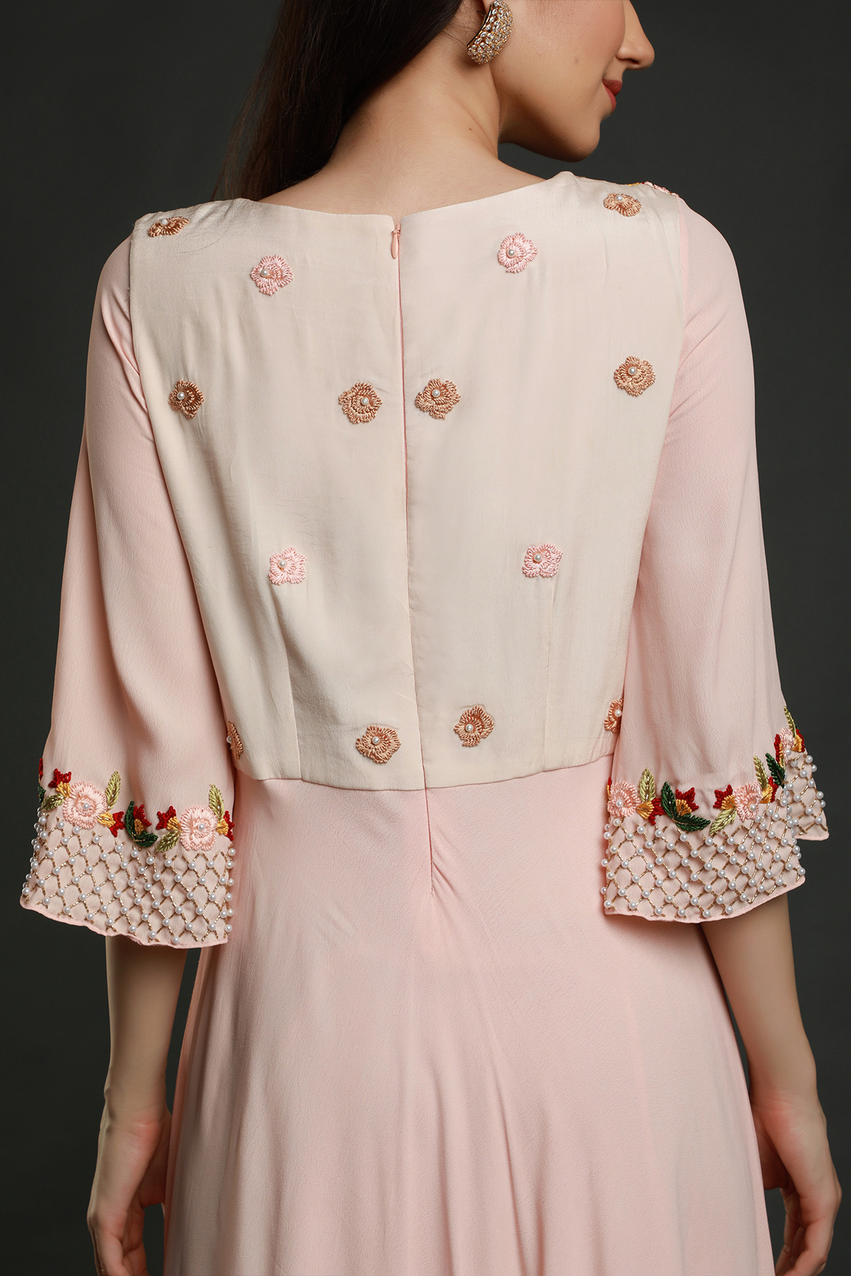 Step into elegance with a Light Peach crepe flared tunic dress. Hand-embroidered yoke, pleated panel, and exquisite detailing for a timeless look.